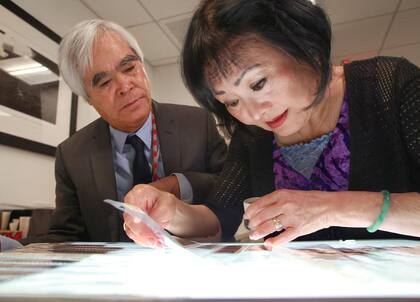 El fotógrafo Nick Ut junto a Kim Phuc, la mujer a quien fotografió cuando era niña y sufrió el ataque de Trang Bang, miran los negativos originales en el archivo de AP al cumplirse el 50 aniversario de aquel ataque