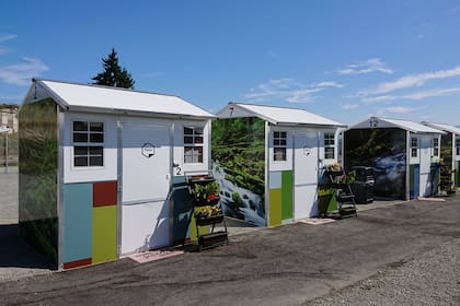 El frente de las casitas con sus alfombras para el ingreso y macetas con flores