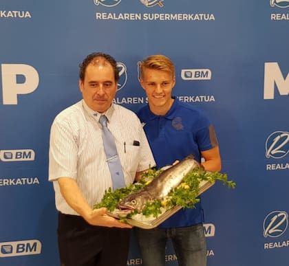 El futbolista sonriendo incómodo mientras sostenía el trofeo marino