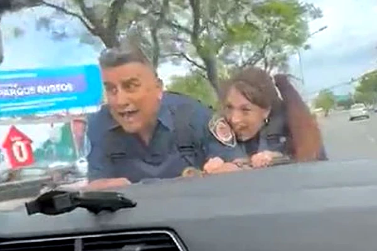 El gesto de desesperación de dos policías mientras son arrastrados en el capot de un automóvil