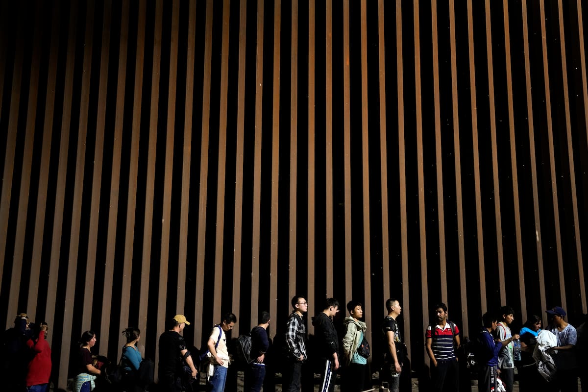 El gobierno de Biden anunció que construirá una sección del muro fronterizo en el sur de Texas. Foto: personas esperan solicitar asilo en Estados Unidos tras cruzar la frontera desde México (archivo)