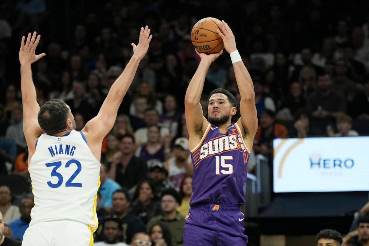El guardia de los Suns de Phoenix, Devin Booker (15), realiza un tiro de tres puntos por encima del