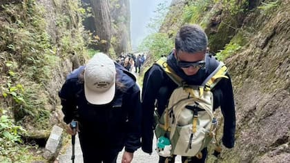 El guía de montaña Wang Zhoutao acompaña a un cliente por las empinadas escaleras del monte Huangshan