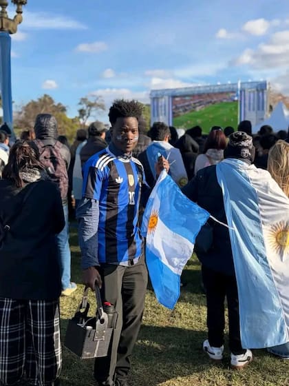 El haitiano John Thomasson Sylvinio en el fan fest con dos emblemas argentinos: la bandera y el mate