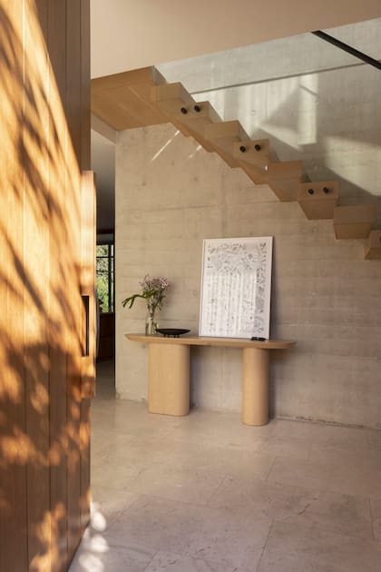 El hall conduce al espacio social de un lado y a la gran cocina por otro. Dressoir de madera (Melazza) con obra de Andrés Latorre (Diderot.art).