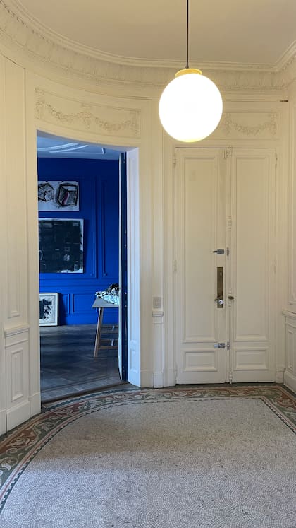 El hall de ingreso del piso de la Fundación, con el piso y molduras originales, y el contraste de color característico de las obras del estudio.