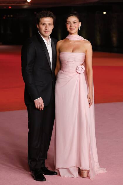 El hijo de David y Victoria Bechham, Brooklyn Beckham, posó junto a su mujer, Nicola Peltz, que vistió un traje Valentino en rosa empolvado de cuerpo drapeado y falda vaporosa y un fulard haciendo juego. Lo combinó con zapatos con plataforma de la misma firma italiana.