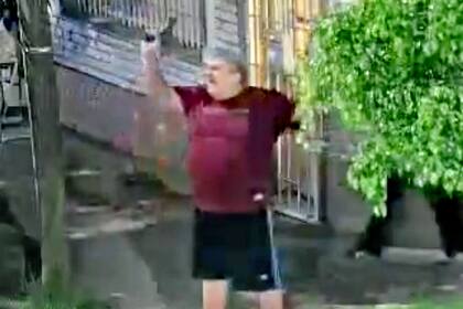 El hombre detenido, de unos 60 años, con las dos armas en alto en una esquina de Lanús