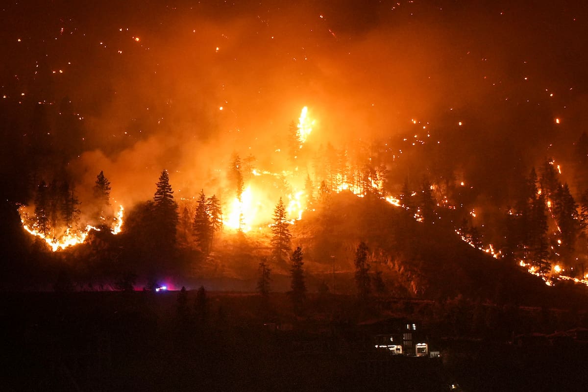 El incendio de McDougall Creek arde en las montañas sobre una vivienda a orillas de un lago en West Kelowna, Canadá, el 18 de agosto de 2023. (Darryl Dyck/The Canadian Press vía AP)