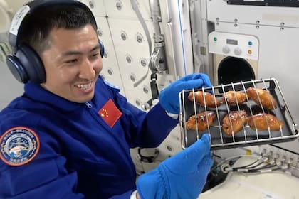 El ingeniero de vuelo espacial de Shenzhou 21, Wu Fei, con la bandeja especial en la que cocinó el pollo a 400 km de altura