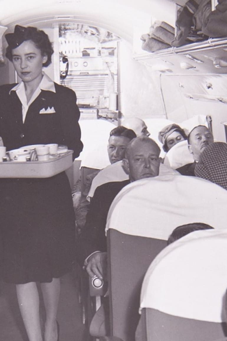 El interior de un Douglas DC-3 y una azafata, en los años previos a la división de los aviones en clases