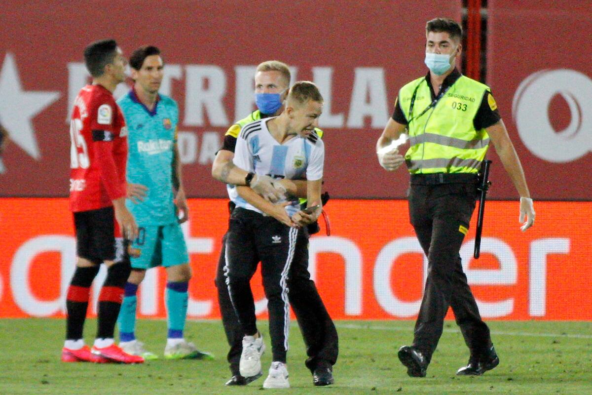 El intruso es sacado de la cancha por un guardia de seguridad. De fondo, Messi