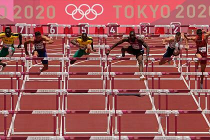 El jamaicano Hansle Parchment, a la izquierda, en su carrera rumbo a la medalla de oro en los 110 metros con vallas. El estadounidense Gran Holloway, tercero de derecha a izquierda, y el jamaicano Ronald Levy, tercero de izquierda a derecha, ganaron plata y bronce respectivamente, el jueves 5 de agosto de 2021, en Tokio. (AP Foto/Charlie Riedel)
