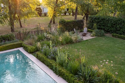 El jardín linda con una zona común; por este motivo, el tradicional
cerco verde fue reemplazado por uno de varillas de alambrado con durazneros en espaldera para integrar las vistas hacia el bosquecito. Los canteros tienen senderos para caminar entre las flores y se generan espacios en el recorrido, como el fogonero.