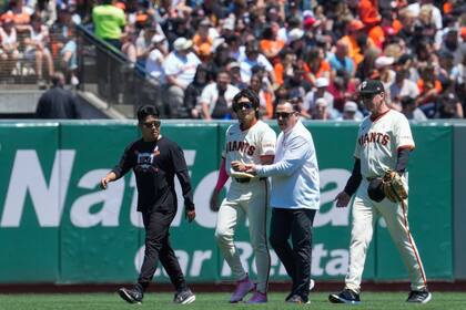 El jardinero central de los Gigantes de San Francisco, Jung Hoo Lee, segundo desde la izquierda, es asistido para salir del campo después de sufrir una lesión durante la primera entrada del juego de béisbol en contra de los Rojos de Cincinnati, el domingo 12 de mayo de 2024, en San Francisco. (AP Foto/Godofredo A. Vásquez)