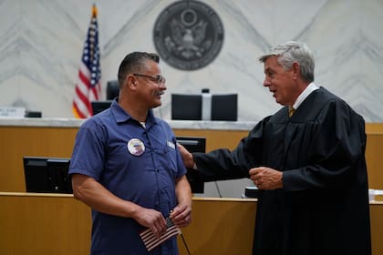 El juez Mark C. Scarsi, a la derecha, agradece a Héctor Ocegueda, veterano del Cuerpo de Infantería de Marina de Estados Unidos, por su servicio militar después de tomarle el juramento para naturalizarse estadounidense el viernes 9 de julio de 2021, en un tribunal federal de Los Ángeles. (AP Foto/Damian Dovarganes)