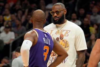 El jugador de los Lakers de Los Ángeles LeBron James habla con el jugador de los Suns de Phoenix Chris Paul (3) en la primera mitad de su juego de NBA el mates 5 de abril de 2022, en Phoenix. (AP Foto/Rick Scuteri)