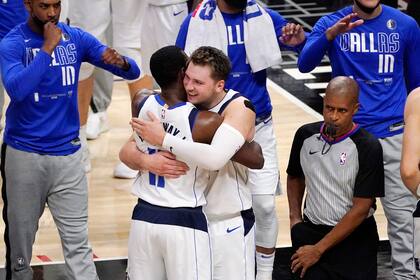 El jugador de los Mavericks de Dallas Luka Doncic, en el centro a la derecha abraza a su compañero  Tim Hardaway Jr.después de que los Mavericks derrotaran 105-100 a los Clippers de los Ángeles en el quinto juego de su serie de primera ronda, en los playoffs de la NBA, el miércoles 2 de junio de 2021 en Los Ángeles. (AP Foto/Mark J. Terrill)