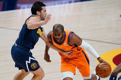 El jugador de los Suns de Phoenix Chris Paul (derecha) elude la marca de su rival de los Nuggets de Denver Facundo Campazzo, en la primera mitad del juego de la NBA que enfrentó a ambos equipos, el 1 de enero de 2021, en Denver.