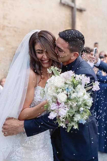 El jugador del Hellas Verona y la modelo italiana, a la salida de la iglesia San Salvatore al Monte con la típica lluvia de arroz. El ramo protagonizado por flores blancas, como rosas y jazmín de leche.