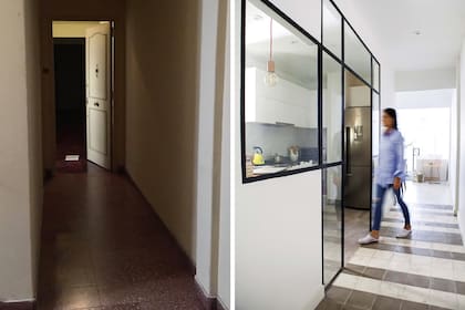 El largo pasillo de acceso corre en paralelo a la cocina (integrada por un cerramiento de vidrio repartido) y desemboca en el comedor.