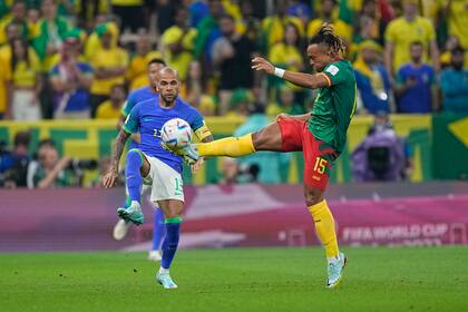 El lateral brasileño Dani Alves (izquierda) pugna por el balón con el camerunés Pierre Kunde durante el partido por el Grupo G del Mundial, el viernes 2 de diciembre de 2022, en Lusail, Qatar. (AP Foto/Pavel Golovkin)