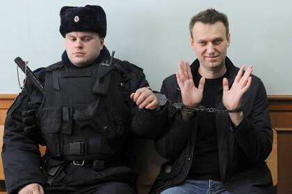 El líder opositor ruso Alexei Navalny (derecha) posa para la prensa mientras está esposado en un tribunal en Moscú, Rusia, el jueves 30 de marzo de 2017. (AP Foto, Archivo)