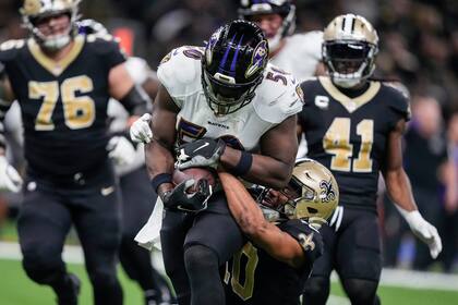 El linebacker Justin Houston (50), de los Ravens de Baltimore corre después de conseguir una intercepción y es derribado por el receptor de los Saints de Nueva Orleans Tre'Quan Smith (10) en la segunda mitad del juego de la NFL, en Nueva Orleans, el lunes 7 de noviembre de 2022. (AP Foto/Gerald Herbert)