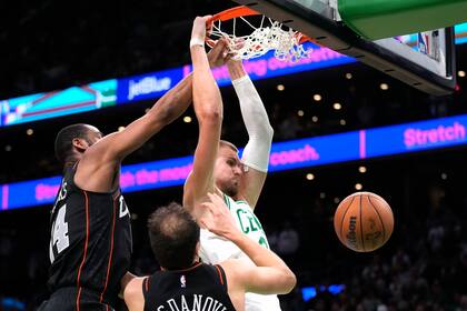 El lituano Kristaps Porzingis, pívot de los Celtics de Boston, realiza una clavada frente a Alec Burks (izquierda) y Bojan Bogdanovic, de los Pistons de Detroit, en la prórroga del partido del jueves 28 de diciembre de 2023 (AP Foto/Charles Krupa)