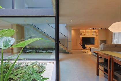 El living comedor que el matrimonio reserva para recibir visitas da la bienvenida a la casa y se conecta con planta alta por la escalera flotante en hormigón.