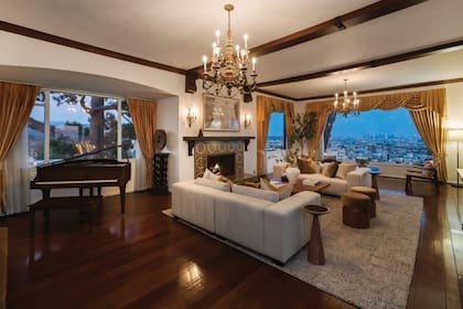 El living, con
un hogar decorado con
azulejos antiguos, vigas
de madera y grandes
ventanales
