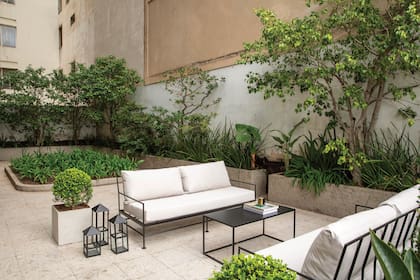 El living conecta con un patio rodeado de árboles y plantas.