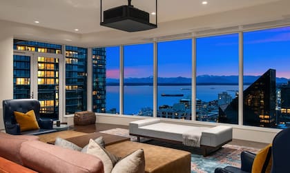El living cuenta con ventanales de piso a techo que ofrecen vistas panorámicas a la ciudad y la bahía