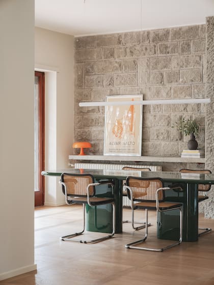 El living se conecta directamente al comedor principal, con quien comparte un mismo lenguaje a través del uso de materiales nobles como la piedra o el roble. Mesa ‘Big’ laqueada en verde (Punto Zero), sillas ‘Cesca’ (diseño de Marcel Breuer para Knoll) y luminaria colgante (Artemide).