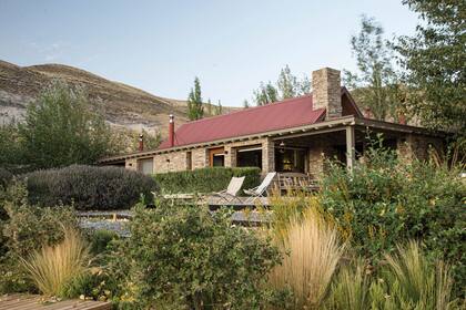 El lodge, construido con materiales típicos de la zona –piedra y techo de chapa rojo–, cuenta con tres habitaciones, un comedor y una sala de estar. Ante un jardín que invita a ser recorrido, una gran galería aterrazada es lugar de disfrute luego de intensos días de aventuras