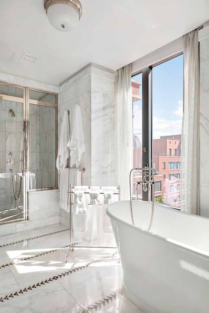El lujoso baño está revestido en mármol blanco y gris.