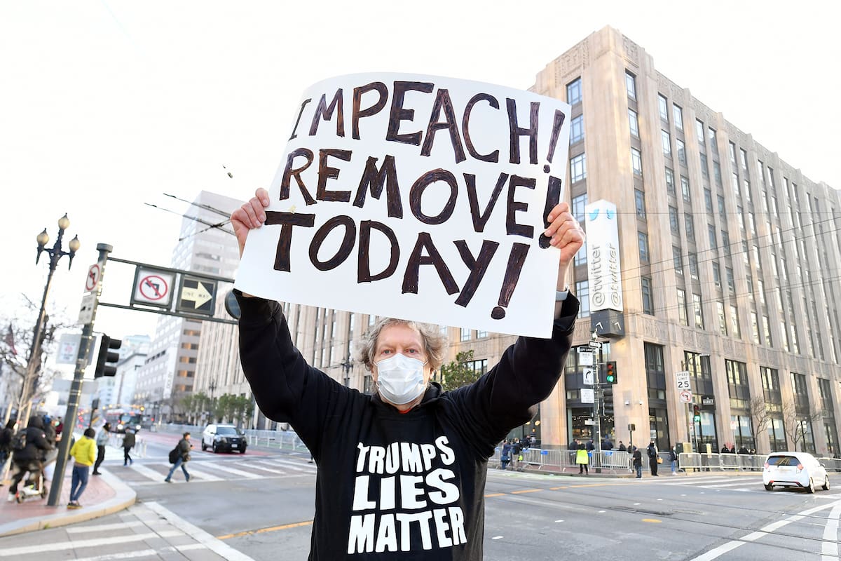 El manifestante Kenneth Lundgreen sostiene un cartel que pide la destitución del presidente Donald Trump mientras la policía armaba barricadas frente a la sede corporativa de Twitter en San Francisco, California, el 11 de enero de 2021