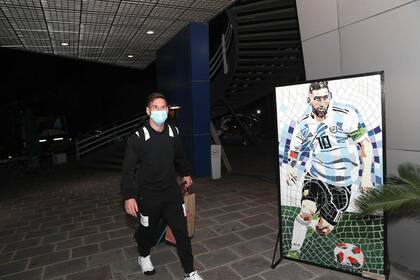 El Messi real, con barbijo, se cruza con el Messi del póster; máximo goleador histórico de las eliminatorias sudamericanas (junto con su amigo Luis Suárez), con 21 tantos, esta noche abrirá el camino rumbo a Qatar 2022