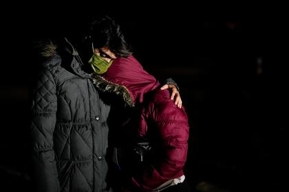 El migrante cubano Mario Pérez abraza a su esposa mientras esperan solicitar asilo luego de cruzar la frontera a Estados Unidos, el viernes 6 de enero de 2023, cerca de Yuma, Arizona. (AP Foto/Gregory Bull)