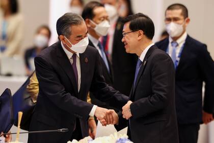 El ministro de Relaciones Exteriores chino Wang Yi, a la izquierda, y el jefe del ejecutivo de Hong Kong, John Lee, se dan un apretón de manos durante el diálogo informal de líderes de la APEC, el 18 de noviembre de 2022, en Bangkok, Tailandia. (Athit Perawongmetha/Foto compartida vía AP)