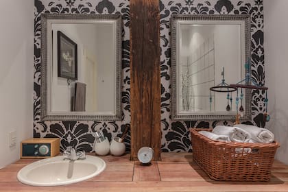 El mismo empapelado que vimos en el living se usó en el baño, como fondo de dos espejos con marco plateado. Al igual que en la cocina, la mesada es de madera.