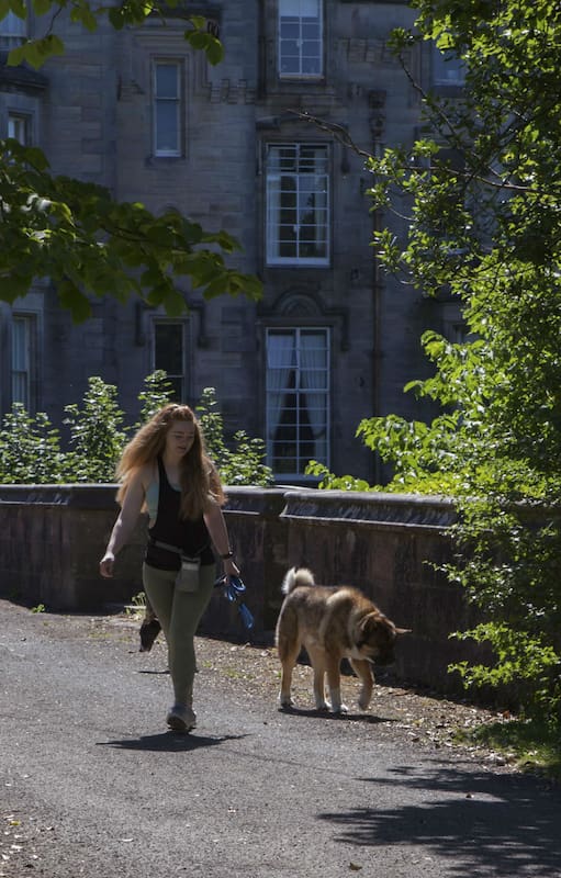 Una mujer lleva su perro con correa en el misterioso puente Overtoun en Dumbarton, Escocia