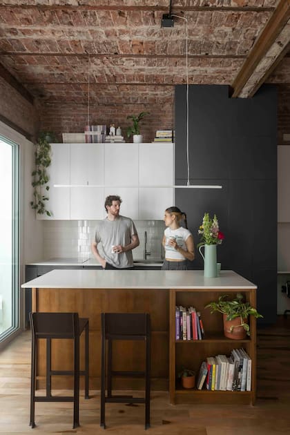 El módulo gris –color también elegido para el bajomesada– contiene la heladera y espacio de guardado. Además, funciona como divisor de la cocina y el escritorio.
