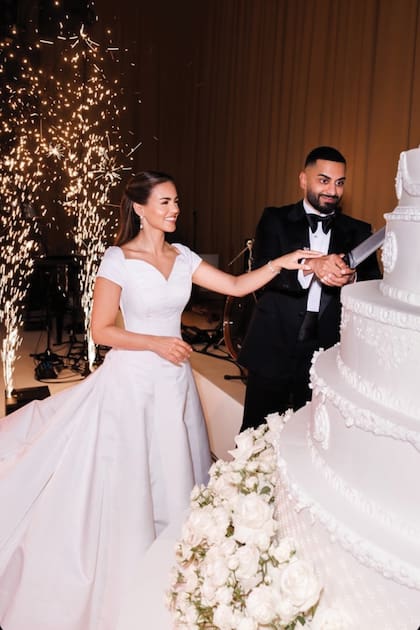 El momento del
primer corte de la torta
de bodas, decorada con
flores blancas.