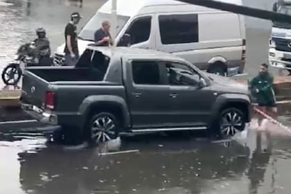 El momento en el que el automovilista embiste contra el vecino que impedía el acceso a una calle inundada