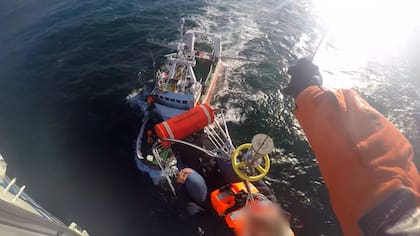 El momento en que el marinero infartado es izado en una canasta de rescate hasta el helicóptero de la Prefectura