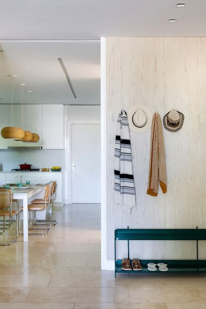 El mudroom marca el paso desde la cocina hacia el family. Allí, zapatero metálico (Brío Muebles) y revestimiento de pared en paraíso laqueado.