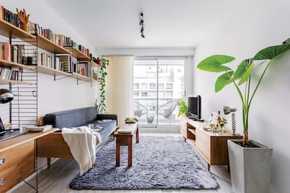 El mueble a medida hecho por Calyfornio sirve como escritorio y continúa como biblioteca desplegándose sobre el sillón.