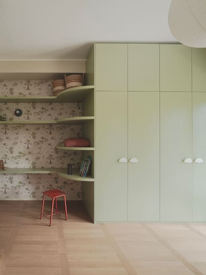 El mueble se continúa con estantes sobre el mismo empapelado de la pared de la cama.
