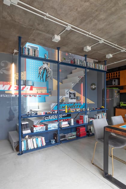 El mural de Cabaio Spirito convive con la biblioteca de chapa azul petróleo. Tubos de led suspendidos (Huup) acompañan el recorrido y permiten iluminar la casa con una sola tecla.